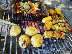 A vibrant display of grilled vegetables and skewers on a barbecue, perfect for outdoor dining and gatherings on the water.