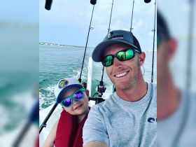 A joyful father and son share a fishing adventure on the water, showcasing the perfect bonding experience while enjoying the great outdoors.