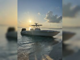 A sleek speedboat named 'Knot die Time' is docked on a serene beach at sunset, showcasing the perfect setting for a relaxing day on the water.