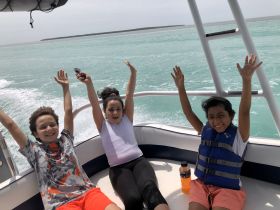 A joyful group of children celebrates aboard a boat, hands raised in excitement as they enjoy their time on the water — perfect for family adventures and fun outings.