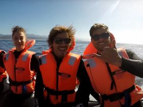 A cheerful group of friends enjoys a thrilling boat ride on the ocean, showcasing the excitement of water adventures with life jackets on.
