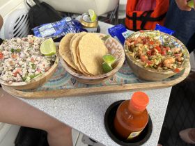 A vibrant display of fresh ceviche, tacos, and salsa served on a boat, perfect for enjoying delicious snacks while out on the water.