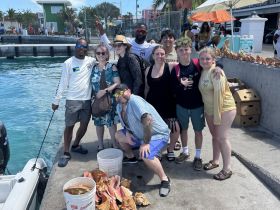 A lively group of friends poses for a photo at the dock, celebrating their day on the water with smiles and camaraderie — a perfect snapshot of beach fun.