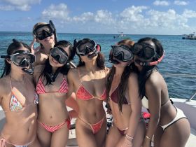 A lively group of friends poses for a fun snorkeling photo on a boat, showcasing their excitement for underwater adventures in crystal-clear waters.