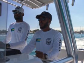Two crew members navigate a boat, showcasing the expertise and professionalism of the team — perfect for those looking to charter a boat in the Bahamas.