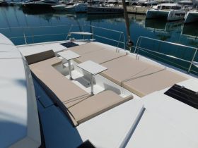 A spacious lounge area on a yacht featuring comfortable seating and tables, perfect for relaxing while enjoying the marina views.