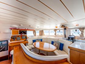 Interior view of a spacious boat cabin featuring a comfortable seating area and helm, perfect for relaxing or navigating on the water.