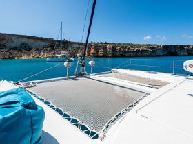 A stunning view of a catamaran anchored in crystal-clear waters, showcasing the beautiful coastline and cliffs in the background — perfect for exploring scenic destinations.