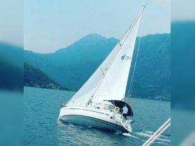 A sailboat navigates through serene waters with majestic mountains in the background, showcasing the beauty of sailing adventures.