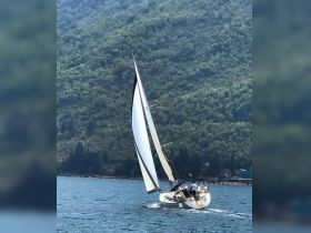 A sailboat gracefully navigates the waters, showcasing the thrill of sailing amidst stunning natural scenery.