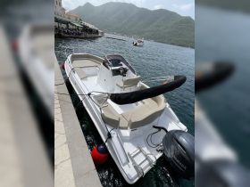 A sleek speedboat docked in a picturesque harbor, surrounded by stunning mountains — perfect for exploring coastal waters.