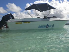 A sleek speedboat named 'AQUAHOLIC 2' anchored in clear turquoise waters, perfect for a day of adventure on the sea.