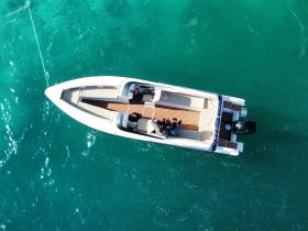 Aerial view of a group enjoying a day on a sleek boat in clear turquoise waters, perfect for adventure and relaxation on the water.