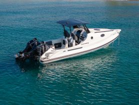 A sleek speedboat glides through clear turquoise waters, showcasing its modern design and powerful twin engines — perfect for thrilling water adventures.