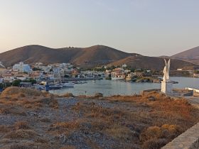 A picturesque view of a harbor surrounded by charming houses and hills, showcasing the serene beauty of island life.