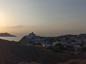 A picturesque sunset view over a coastal village, showcasing the serene beauty of the island landscape — perfect for capturing the essence of tranquil getaways.