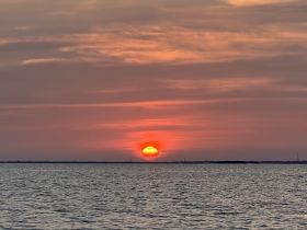 A stunning sunset over tranquil waters, creating a picturesque backdrop perfect for evening boat cruises.