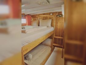 Cozy interior of a boat cabin featuring bunk beds and wooden accents, perfect for comfortable overnight stays on the water.