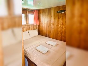 Cozy cabin interior featuring a comfortable double bed with fresh linens and towels, perfect for relaxing on a boat getaway.