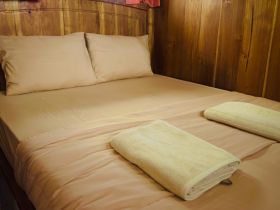 Cozy cabin interior featuring a neatly made bed with soft linens and towels, perfect for relaxing on a boating adventure.