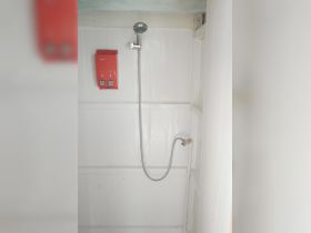 Interior view of a boat shower area, featuring a showerhead and control panel, ideal for refreshing after a day on the water.