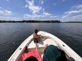 A group enjoys a relaxing day on the water, taking in the beautiful scenery from the bow of their boat. Perfect for summer outings and creating lasting memories.