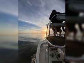 A serene sunset view from a boat with guests enjoying the moment — perfect for capturing the beauty of evening cruises on the water.