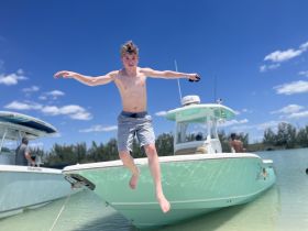 A young boy joyfully jumps off the side of a boat into the water, capturing the essence of summer fun and water activities.