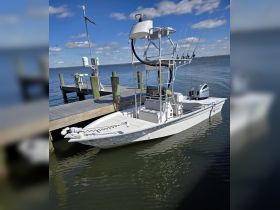 A sleek center console boat docked at a pier, showcasing its fishing gear and pristine design, perfect for a day on the water.