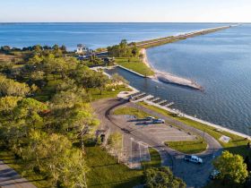 Aerial view of a waterfront area with a boat ramp and surrounding greenery, showcasing a serene landscape ideal for boating activities.