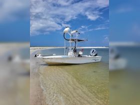 A sleek speedboat anchored on a sandy shore, perfect for fishing trips or leisurely days on the water.