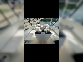 A clean and modern helm area of a boat featuring seating and control panels, perfect for navigating the waters in comfort.