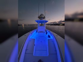 A cozy view of the boat's helm illuminated by blue lighting, showcasing the interior space perfect for evening cruises.