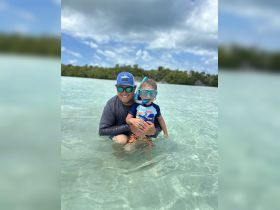 A joyful moment captured as a father and son enjoy snorkeling together in shallow waters, creating unforgettable family memories in a tropical paradise.