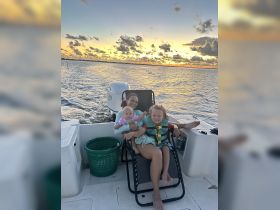 A joyful family enjoys a sunset on the water, with children relaxing on deck — a perfect moment for creating lasting memories while boating.