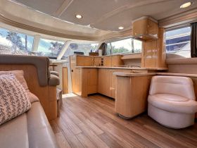 A spacious and elegantly designed interior of a boat, featuring comfortable seating and a well-equipped kitchen area, perfect for relaxing and entertaining while on the water.