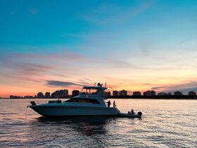 A stunning sunset view featuring a boat with people enjoying the evening, set against a vibrant city skyline — perfect for capturing memorable moments on the water.