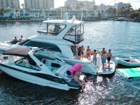 A lively group enjoys a day on the water, with activities including swimming and socializing on a luxurious yacht — perfect for summer parties and gatherings.