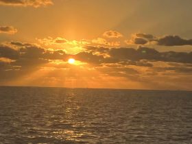 A stunning sunset over the ocean, casting golden hues across the water — perfect for capturing the beauty of a tranquil evening on the sea.