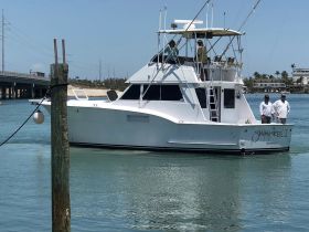 The 'Swingin' Reel II' boat is seen underway with crew members on deck, showcasing a perfect day for fishing in the beautiful waters of Islamorada, Florida.