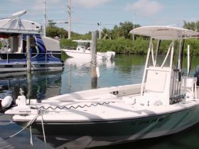 A well-maintained center console boat docked in calm waters, surrounded by lush greenery — perfect for fishing or day trips.