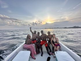 A joyful group of friends poses on a boat at sunset, capturing the essence of a fun day on the water — perfect for memorable outings and celebrations.