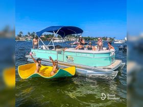 A lively group enjoys a fun day on the water aboard a pontoon boat, with drinks in hand and friends swimming nearby — the perfect setting for a summer party.