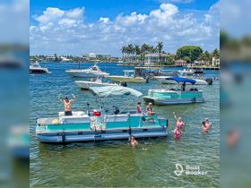 A lively group enjoys a fun day on the water, celebrating aboard a pontoon boat while some swim nearby — the perfect sandbar stop for summer adventures.
