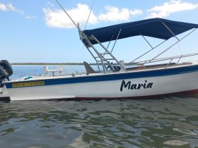 A side view of the boat named 'Maria' docked in calm waters, showcasing its sleek design and tranquil surroundings.