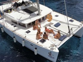 A lively group enjoys a day on a catamaran, sunbathing and celebrating together in crystal-clear waters — perfect for summer outings and memorable gatherings.