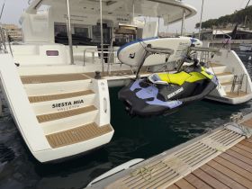A close-up view of the 'Siesta Mia' catamaran featuring a jet ski and paddleboard, showcasing the onboard amenities available for water activities.
