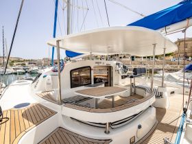 A spacious interior view of a catamaran's helm and seating area, showcasing the elegant design and comfort features ideal for relaxing on the water.
