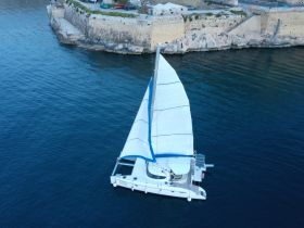 Aerial view of a sleek catamaran sailing through calm waters, showcasing its elegant design and perfect for leisurely cruises.