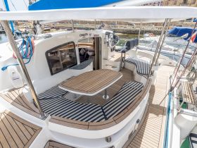 A spacious interior view of a yacht's helm and seating area, showcasing comfortable striped cushions and a well-designed layout for relaxation and navigation.